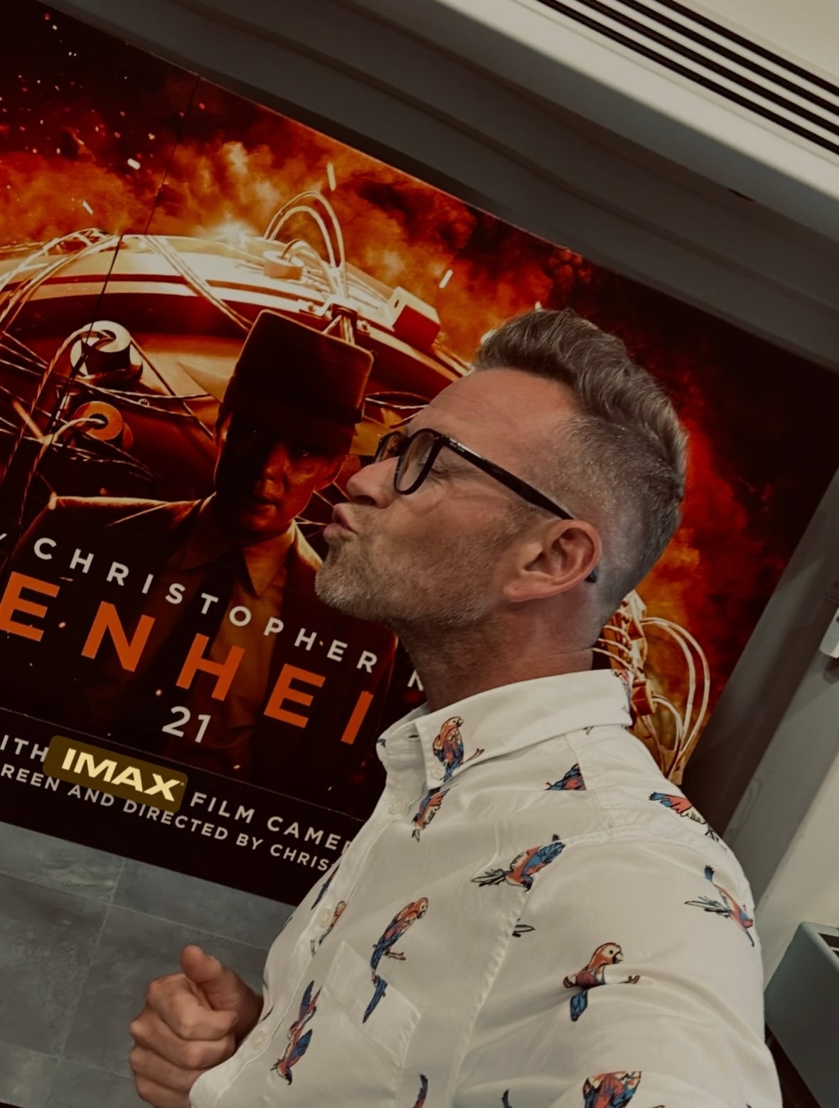 Man standing in front of an Oppenheimer movie poster.