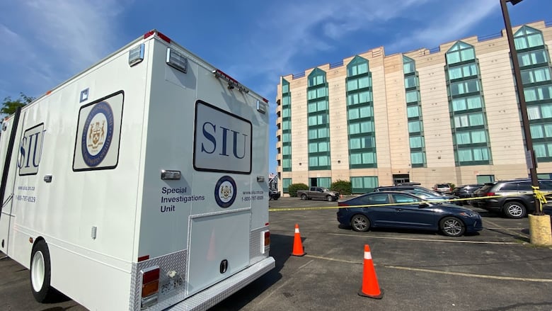 A van marked SIU parked in a lot by a hotel. 