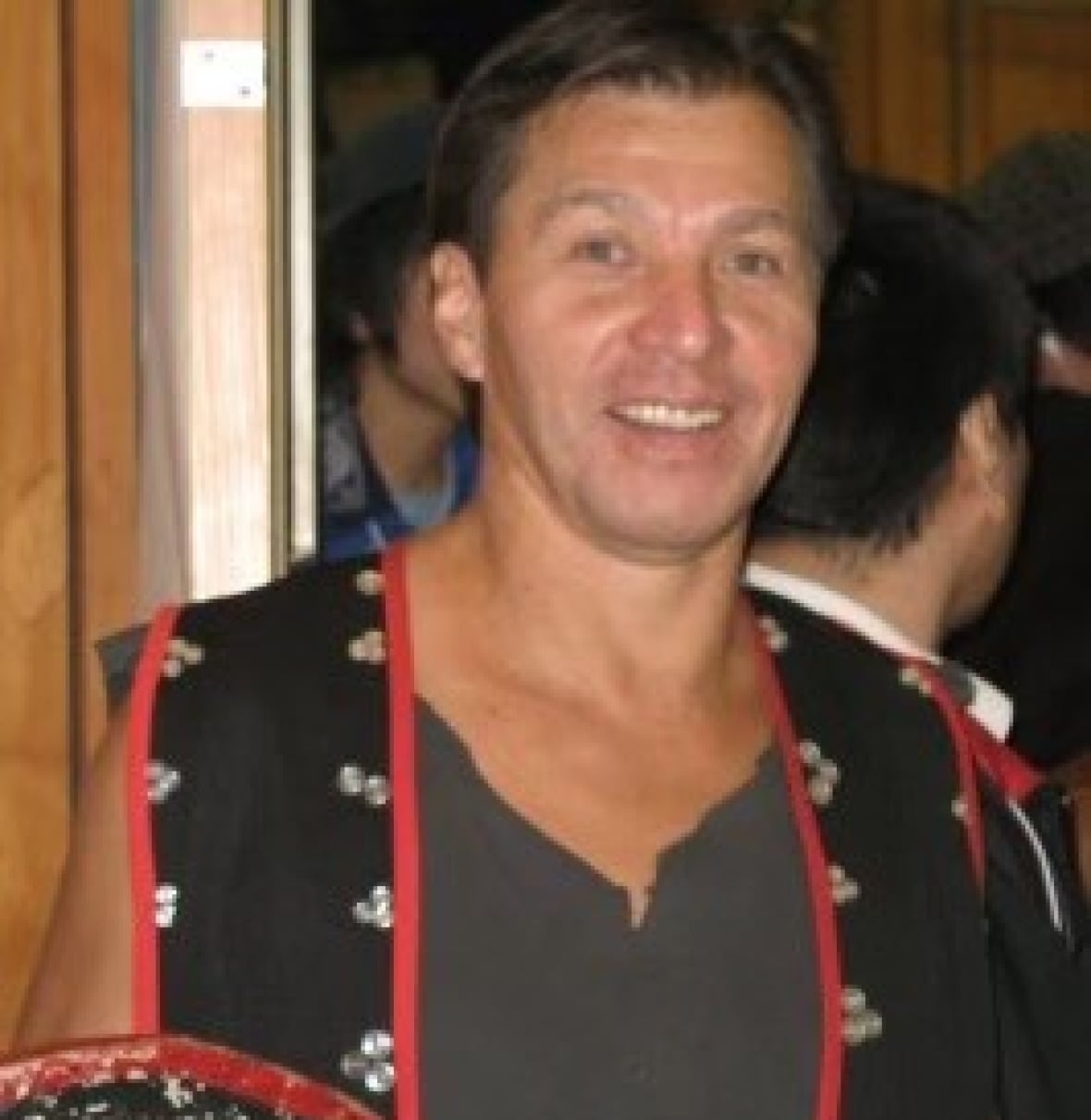 A man smiles for a photo wearing a button vest.