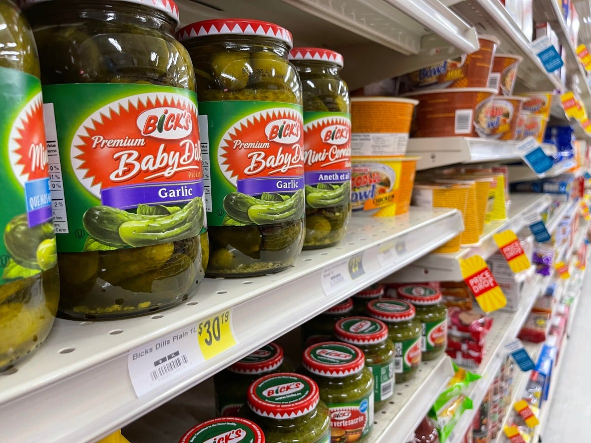 Isole of groceries with bundles of pickles in the foreground