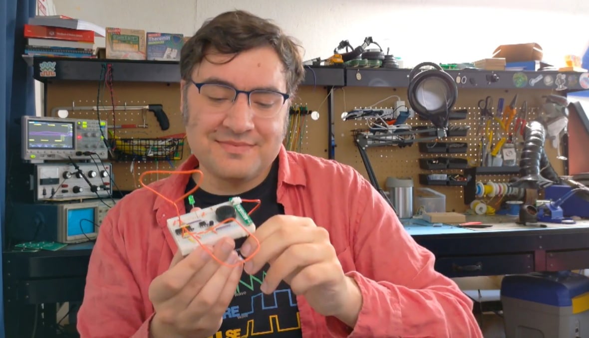 A man holds a gadget with wires