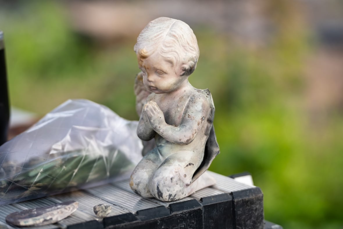 A porcelain angel sits on a table with its hands together.