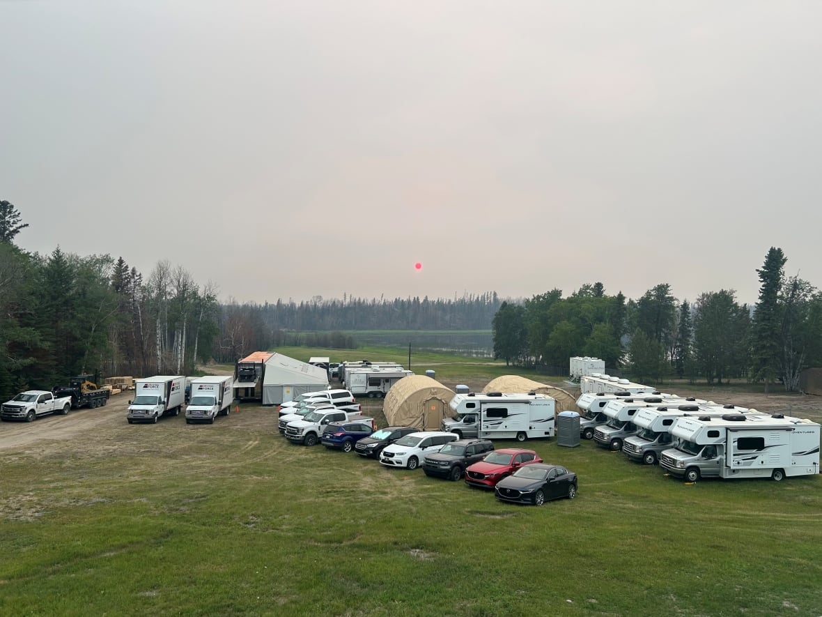 motor homes, tents and cars sit on a large field. 