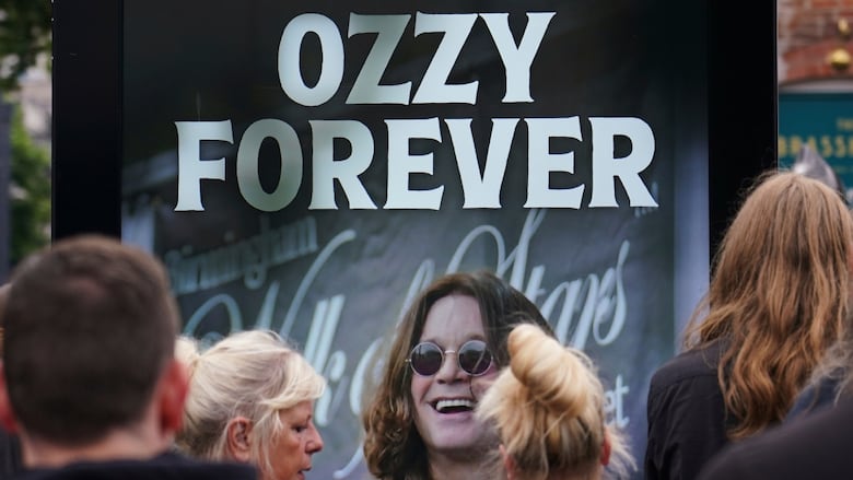 An image of the late Ozzy Osbourne is seen in Birmingham, England, where thousands of fans gathered to watch a funeral procession for the Black Sabbath frontman.