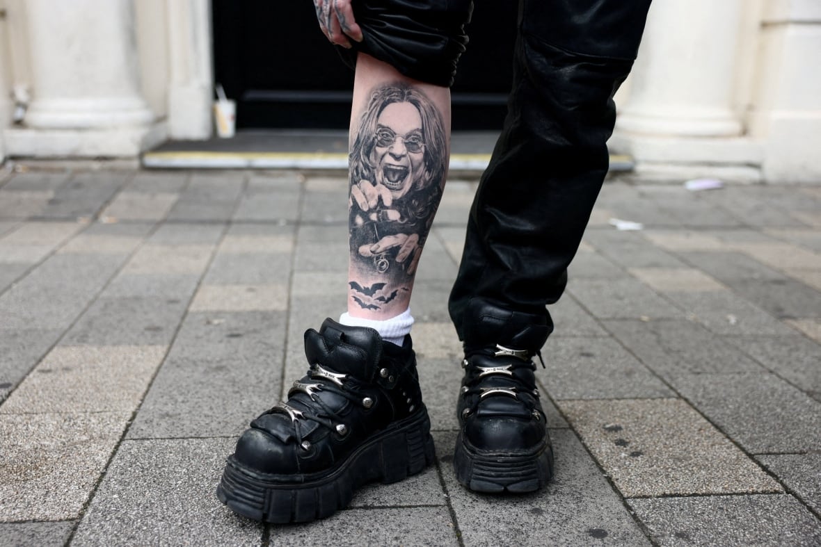 Een vrouw toont haar tatoeage van Ozzy Osbourne in Birmingham, Engeland, op de dag dat de begrafenisstoet van de rocker door de stad reed.