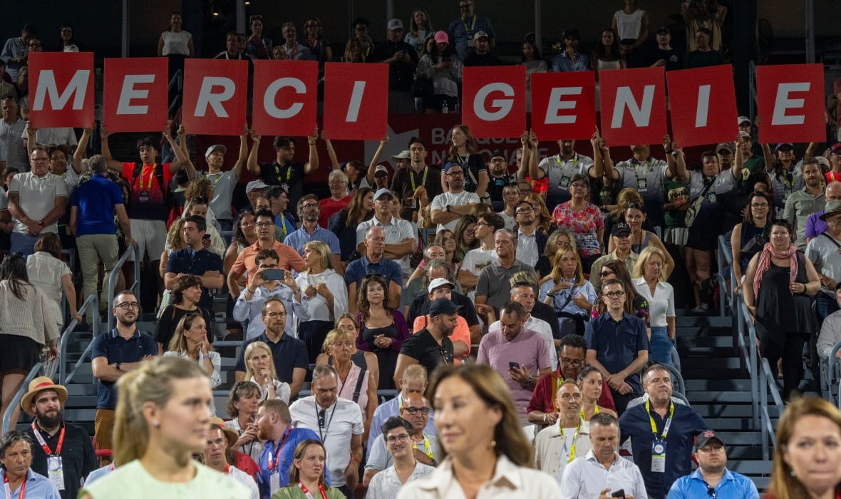 The crowd holds up big red letters that say 'Merci Genie.'