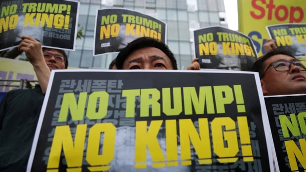 Activists hold signs during a protest against U.S. President Donald Trump's tariffs policy.