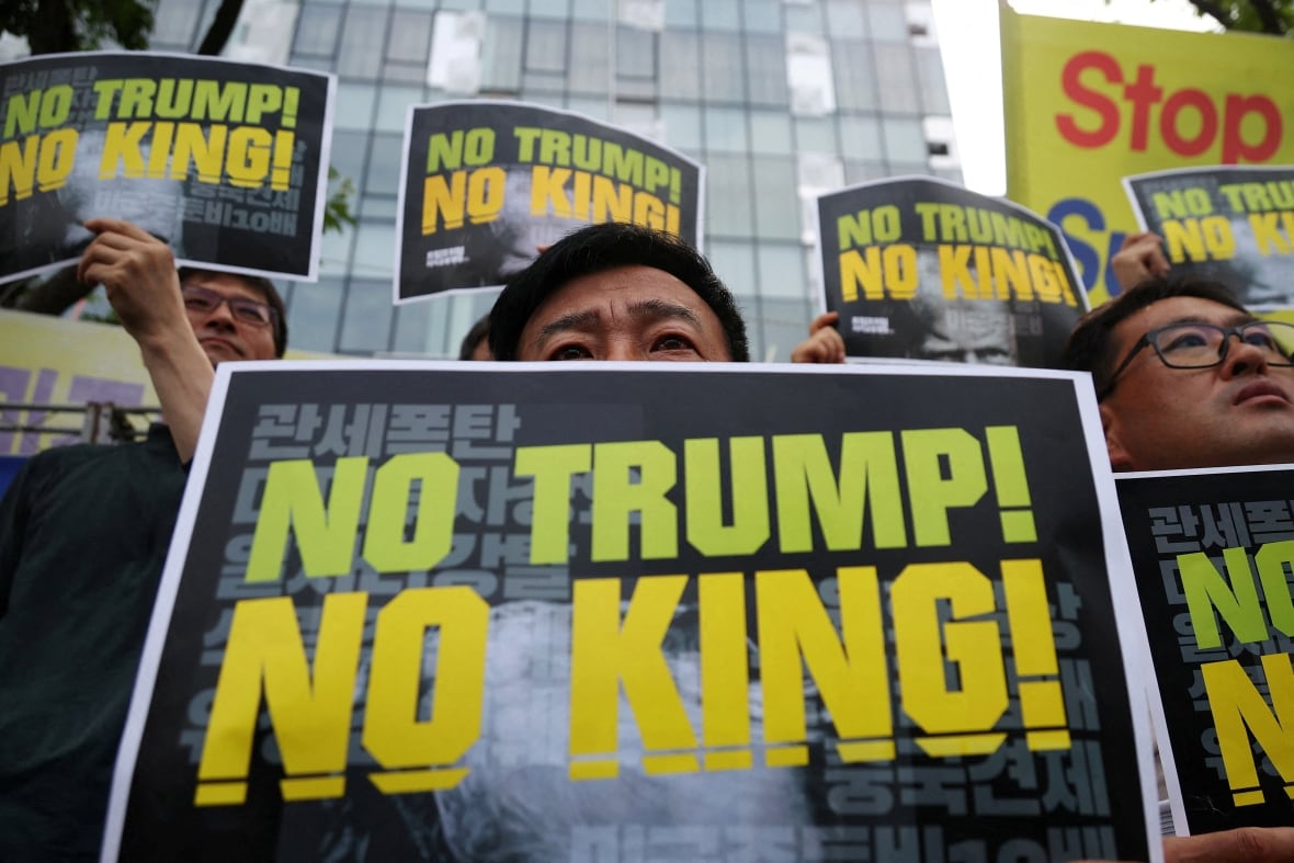 Activists hold signs during a protest against U.S. President Donald Trump's tariffs policy.