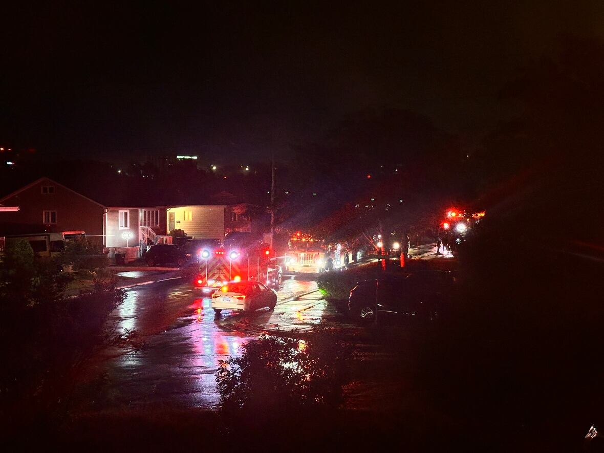 A wet street with a firetruck parked on a residential street.