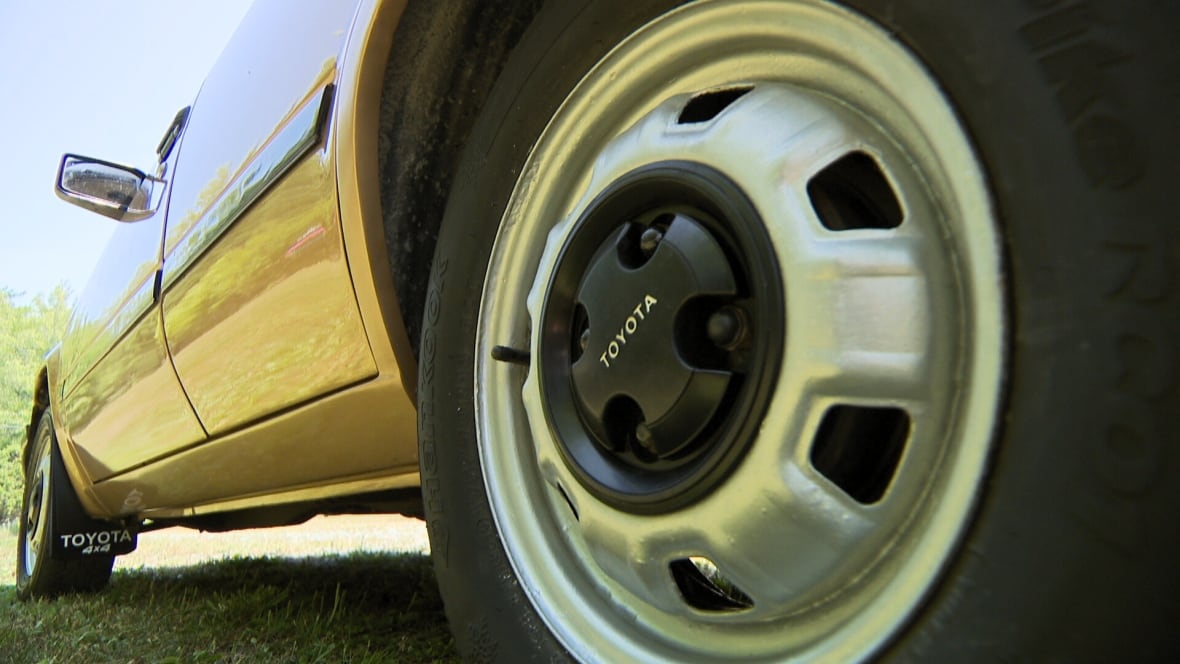 En primer plano se ve la rueda de un coche y detrás se ve el resto del vehículo.