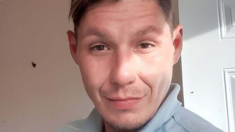 A man in his 30s with blonde hair and brown eyes in a blue polo shirt.