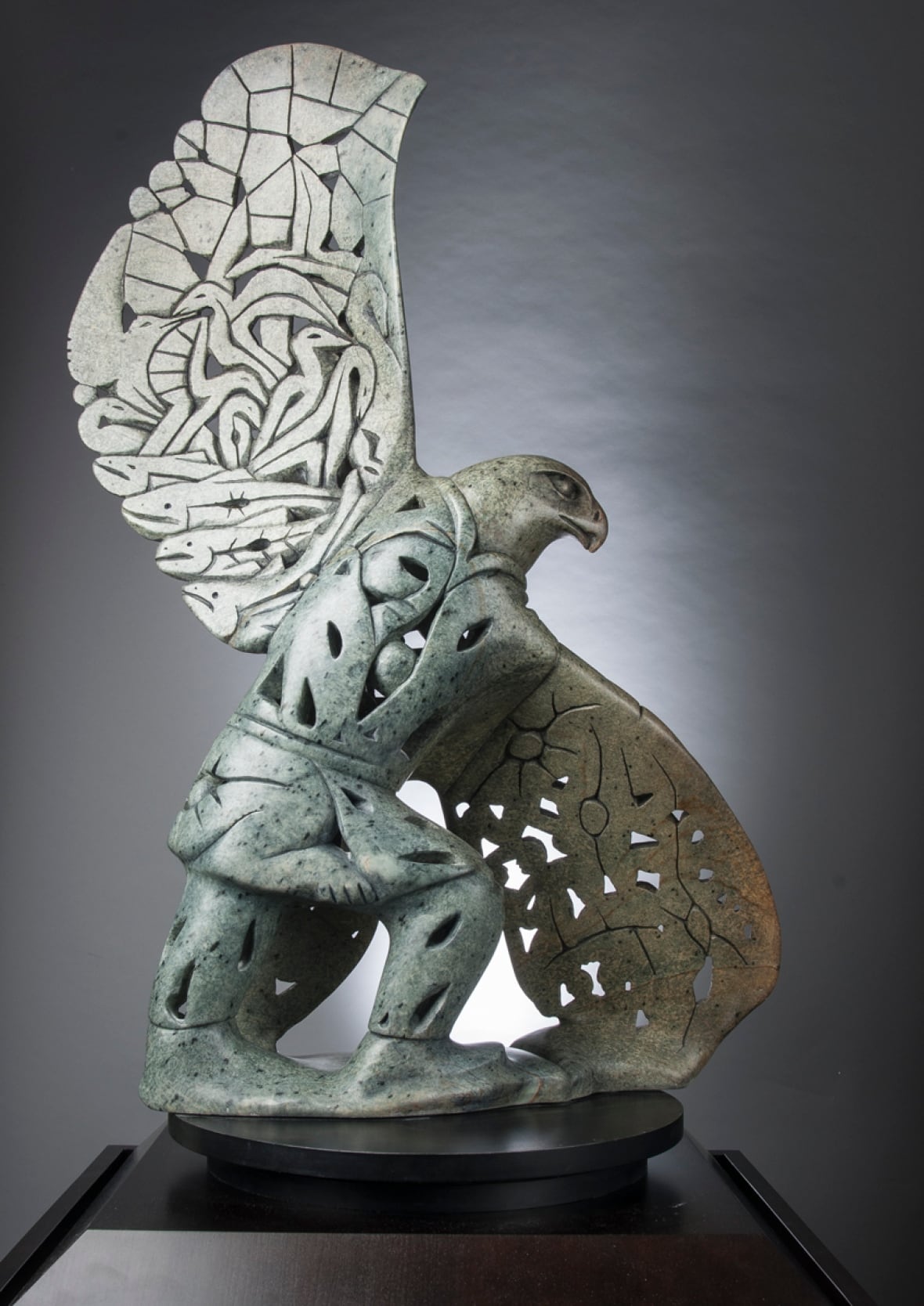 A soapstone sculpture of a creature whose head and upper body is that of a majestic bird, and whose lower body is that of a human.