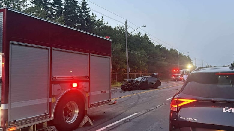 A fire truck parked close to a smashed-up black car.