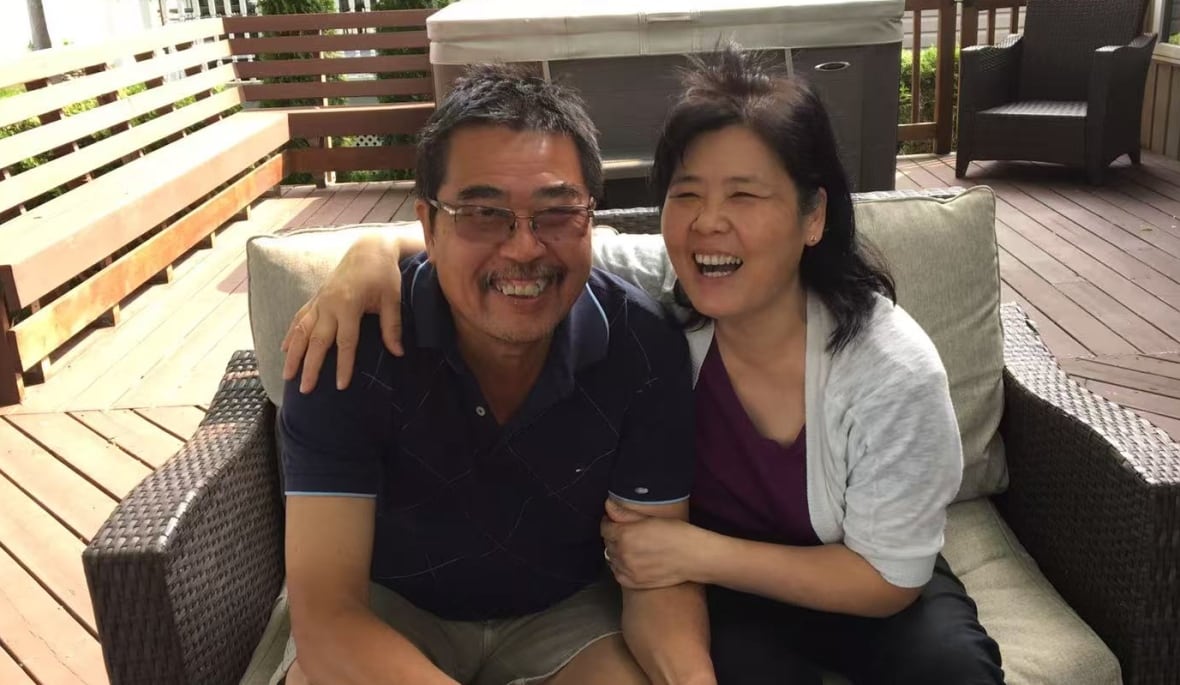 A couple laughs on a patio.
