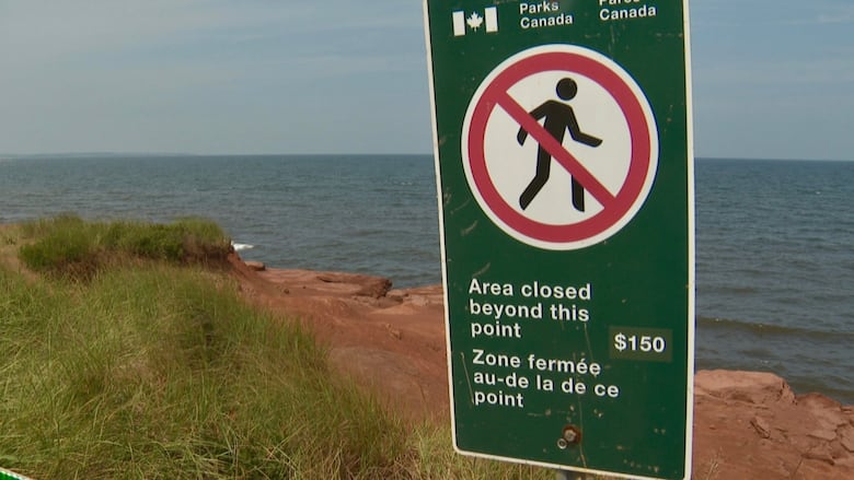 Warning sign by a cliff indicating no entry beyond this point with a $150 fine