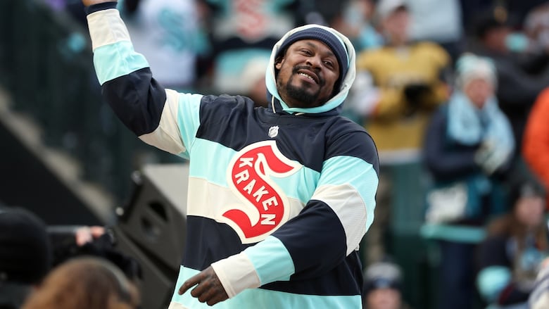 A man raises his hands and salutes fans at a hockey game.