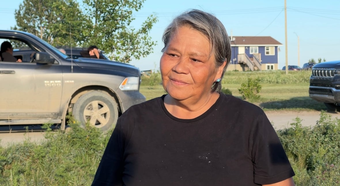 A woman smiles softly while looking at someone to the left of the camera.