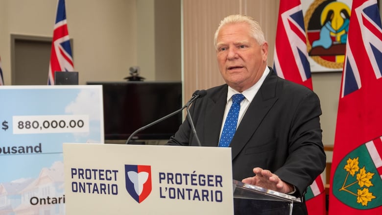A man in a suit talks at a podium.