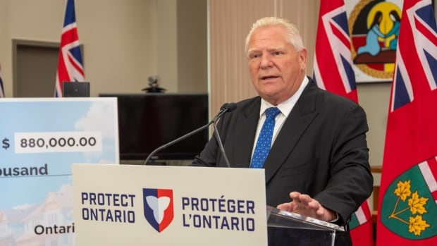 A man in a suit talks at a podium.