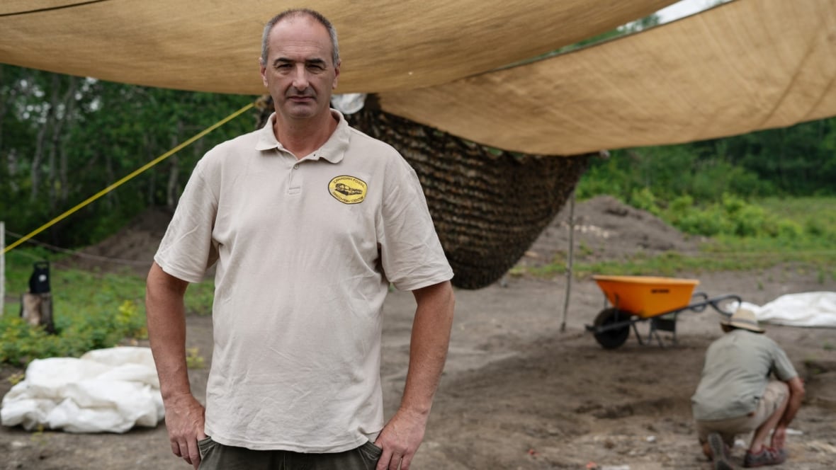 Meet 'Walt,' the 80-million-year-old mosasaur named after the Texas teen who dug it up on the Canadian Prairie 8 A man with short hair and a beige shirt looks at the camera while someone in the background in a crouch digs at a fossil site.