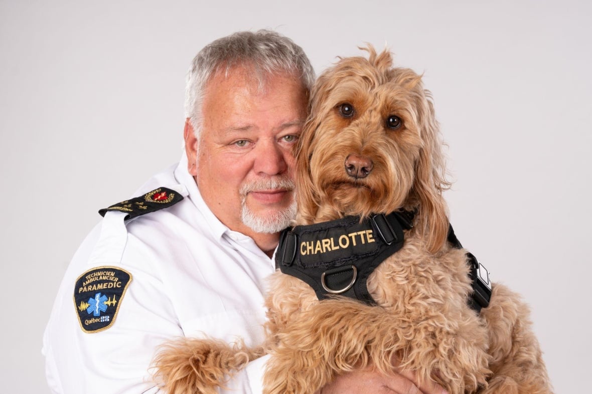 A man in a parademic uniform hugs a dog