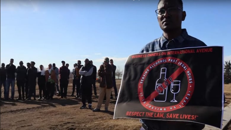A man carries a sign that says in part Serving alcohol past legal hours is costing us lives.