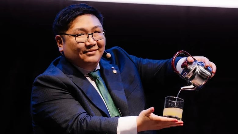 A man pouring a drink as part of a magic trick, wearing a suit.