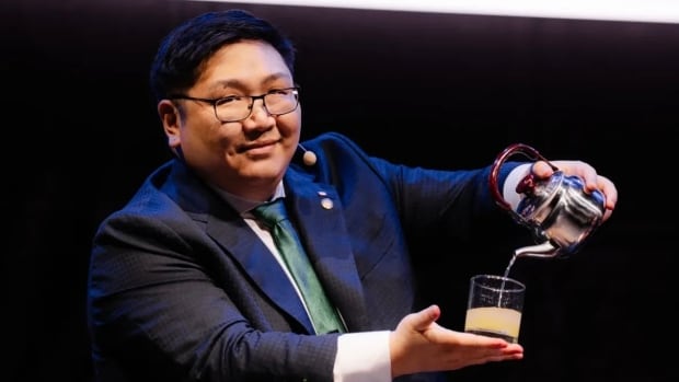 A man pouring a drink as part of a magic trick, wearing a suit.