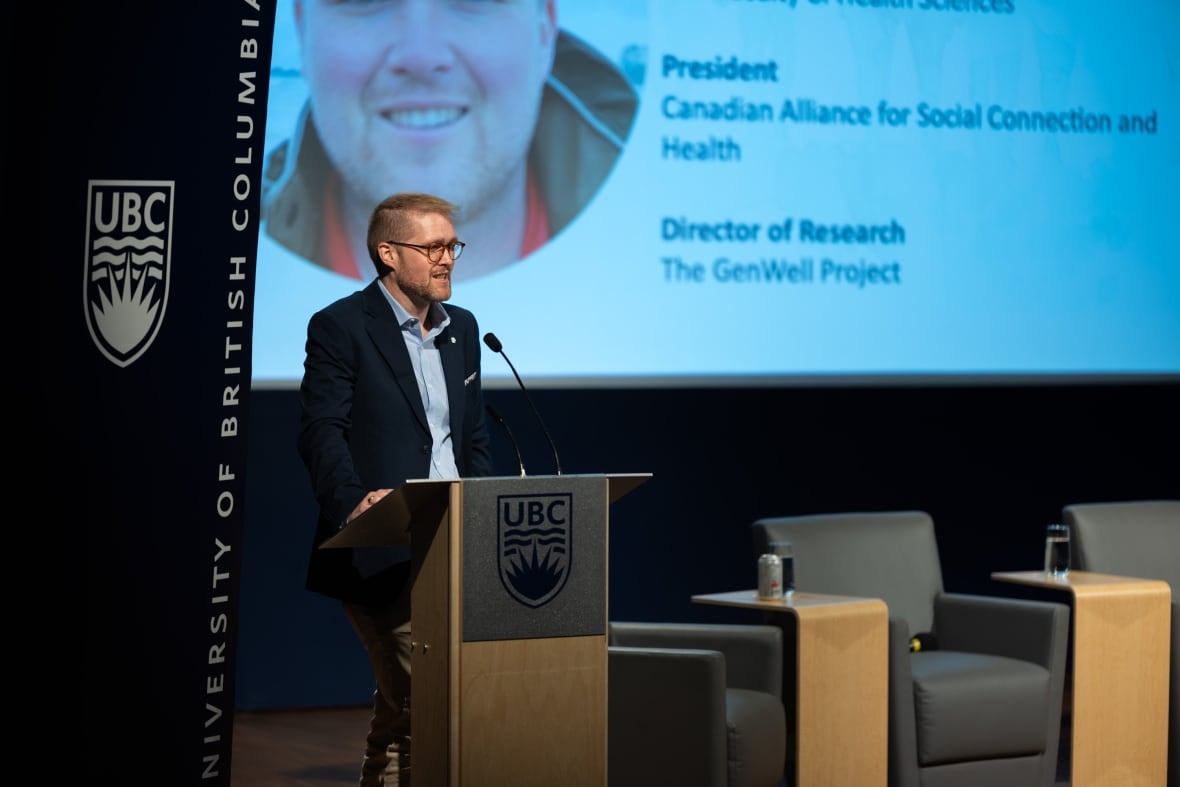 Kiffer Card stands at a podium on stage, giving a lecture/presentation.