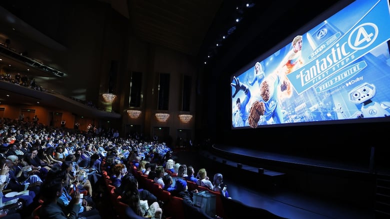 People in a packed movie theatre look at a promo image for the Fantastic Four: First Steps movie.