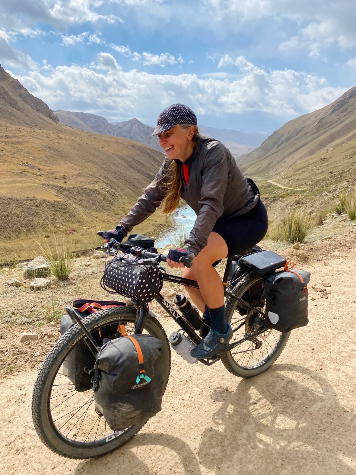 Una mujer sentada en una bicicleta en las montañas sonriendo