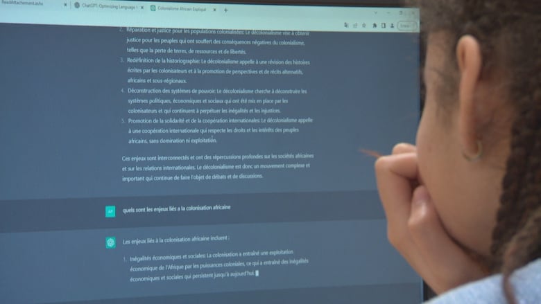 A close-up image of a computer screen showing ChatGPT prompts and a female student seen from behind working on a classroom assignment.