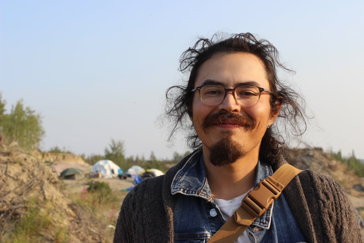 A man with a long dark hair pulled back and glasses.