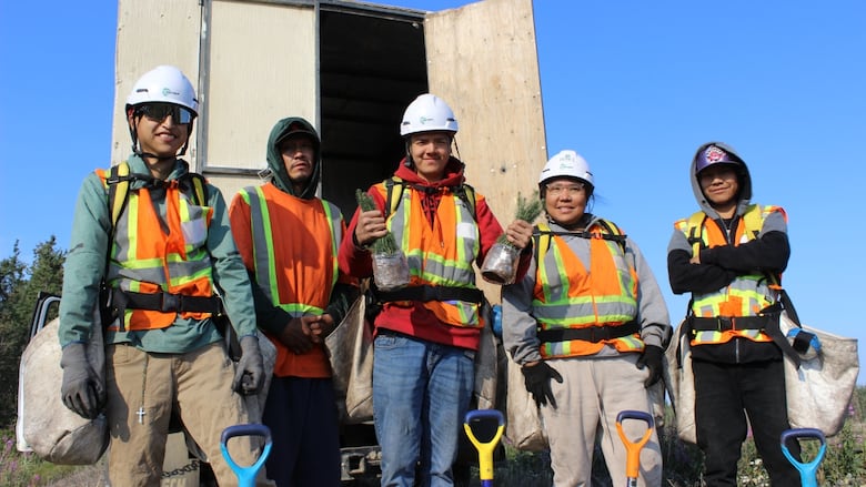 A group of five people in safety vests wearing tree planting bags around their waists.