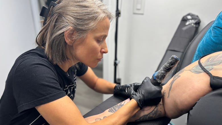 Parnell is tattooing a woman's forearm.