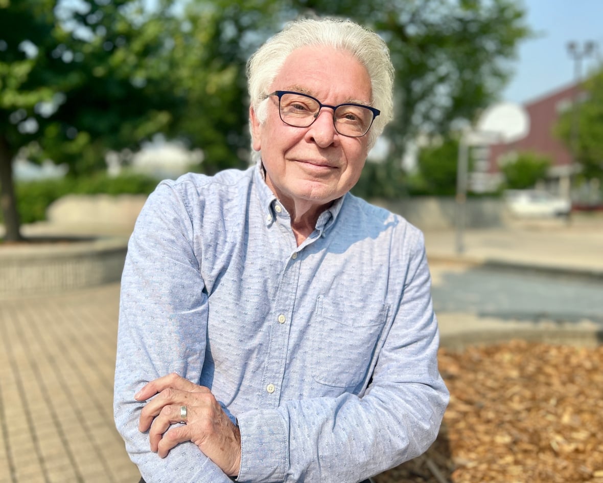 Dr. Bruce Martin sitting outside a tree. Wear glasses and look at the camera.