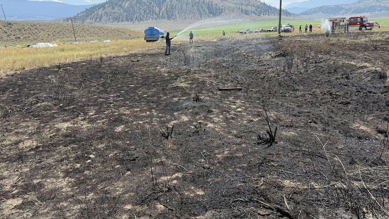 Firefighters at charred grass near Ashcroft, B.C.