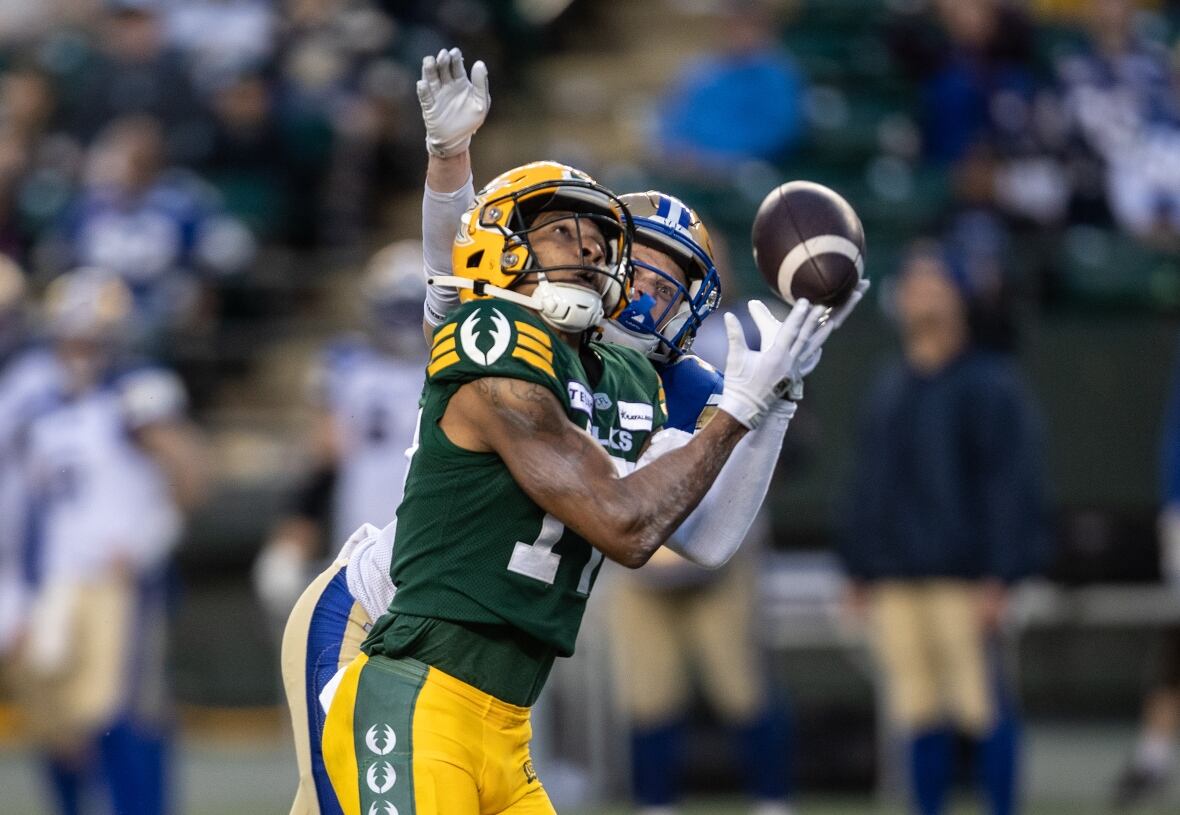A player in a green uniform catches a football.