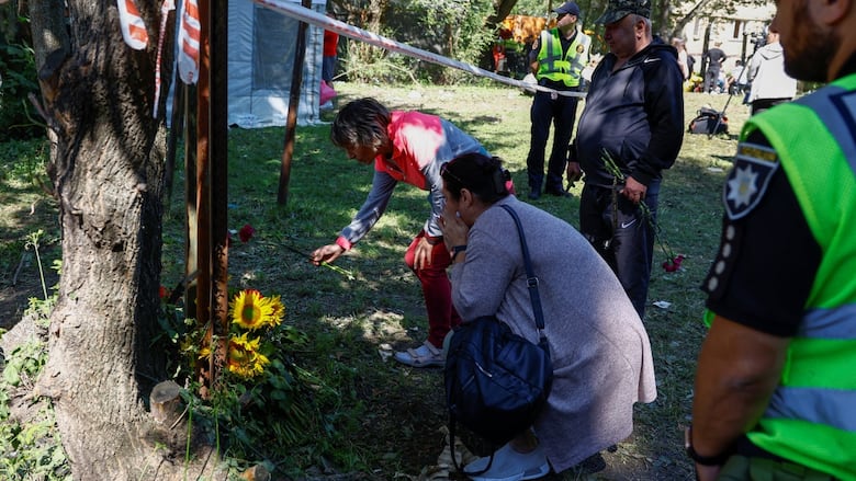 Residents place flowers in memory of victims at the site of an apartment building that was hit by missiles.