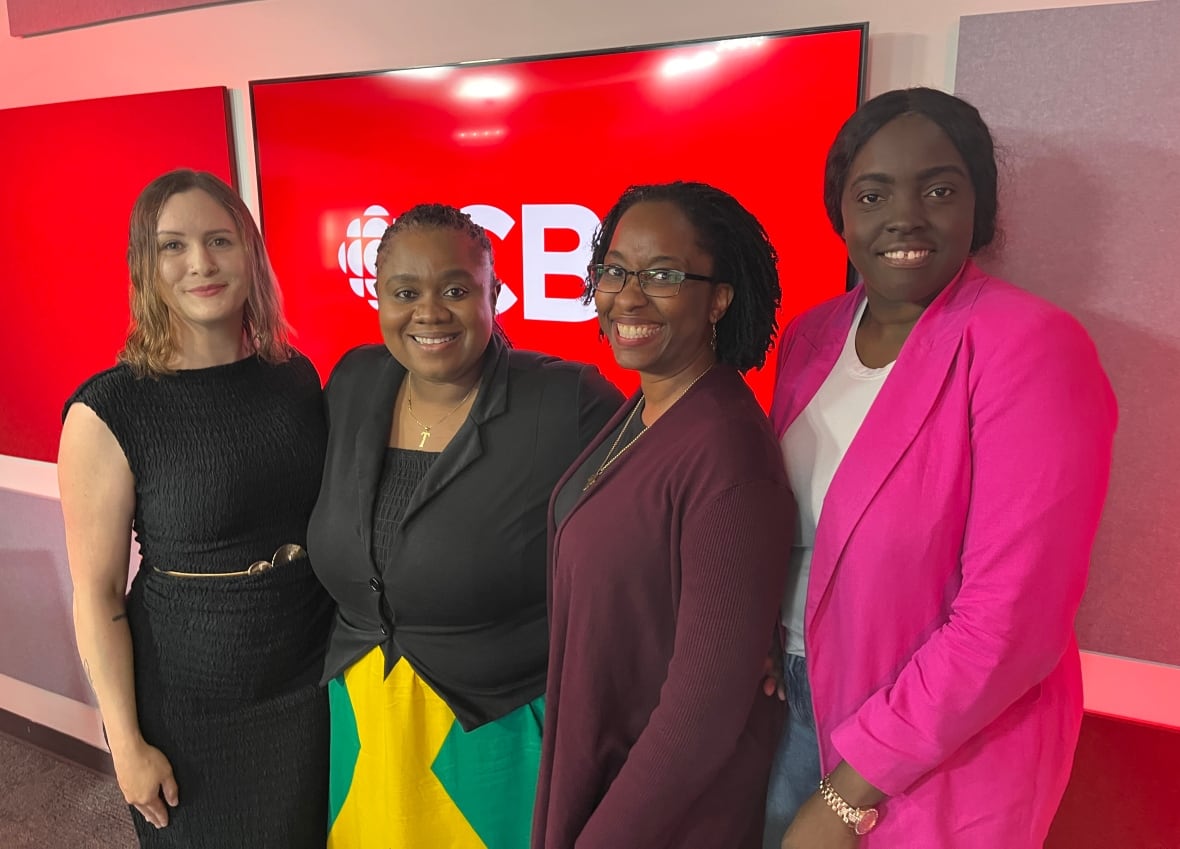 Four women standing next to each other and smile. Three are Jamaican-African and the fourth is Caucasian. 