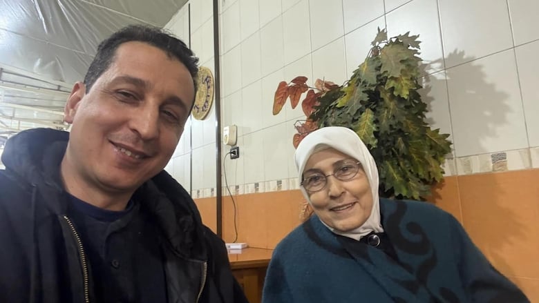 A man and a woman in a hijab smile at the camera in a selfie.