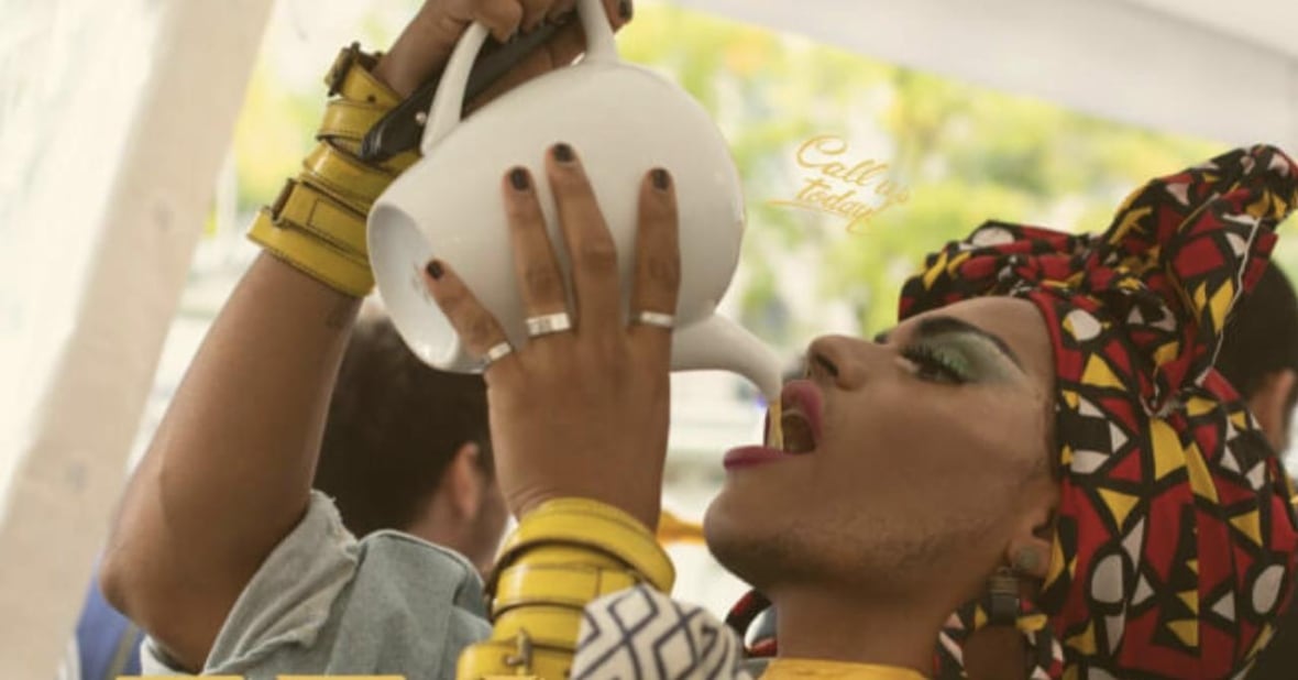 A drag queen drinks tea directly from the teapot. 