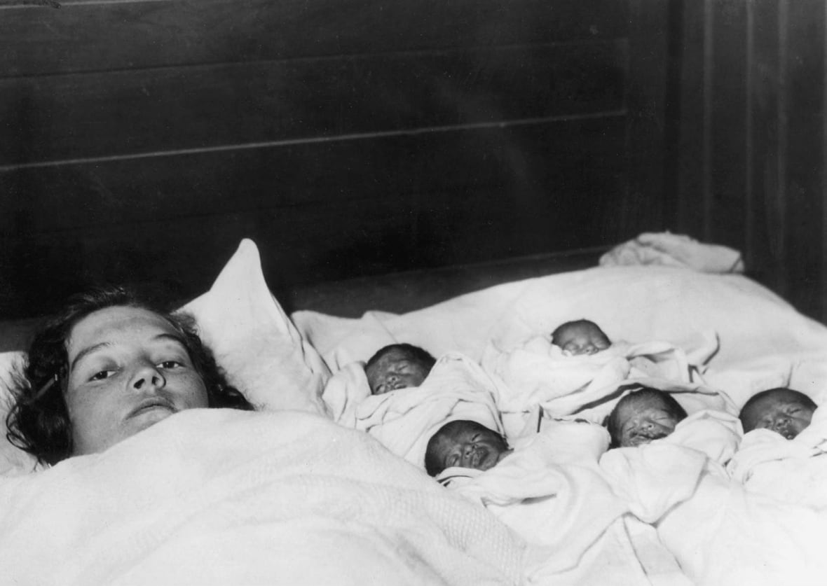 The Dionne quintuplets in bed with their mother, Olivia Dionne