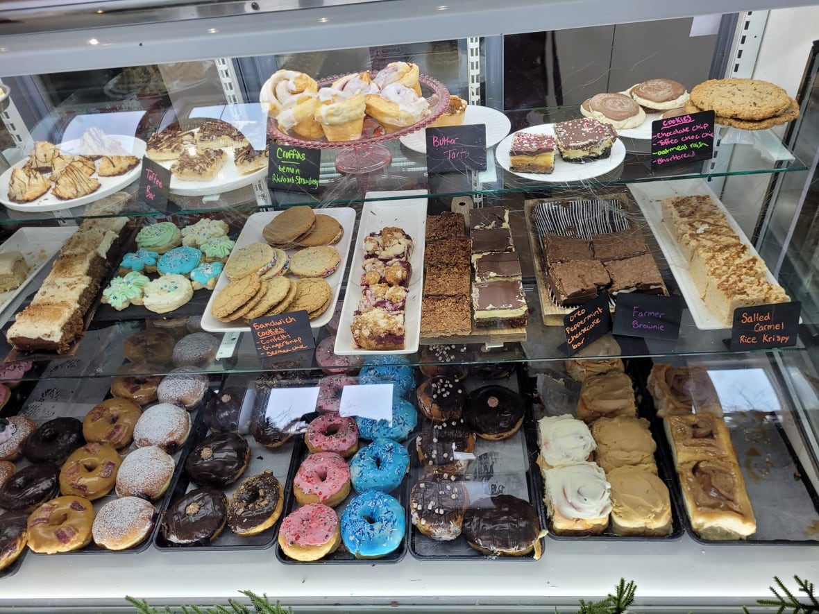 A display case shows multiple donuts and other baked goods.