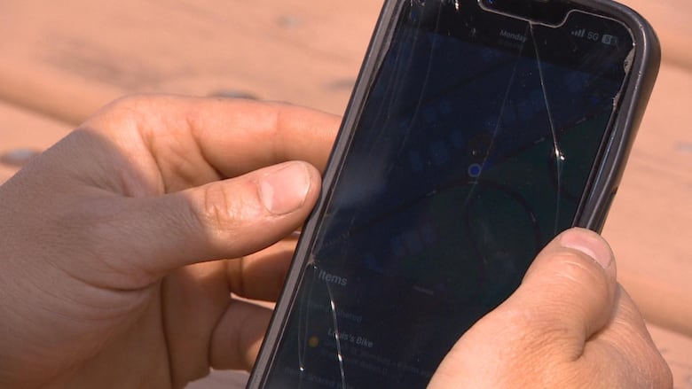 A closeup of Louis' hands.  He's holding his phone and watching his app to see where his bike is.