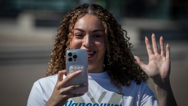 A woman takes her own picture at a news conference, pointing her phone at the reporters off camera.