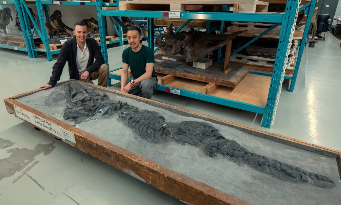 Two men pose with a fossil for a photo.
