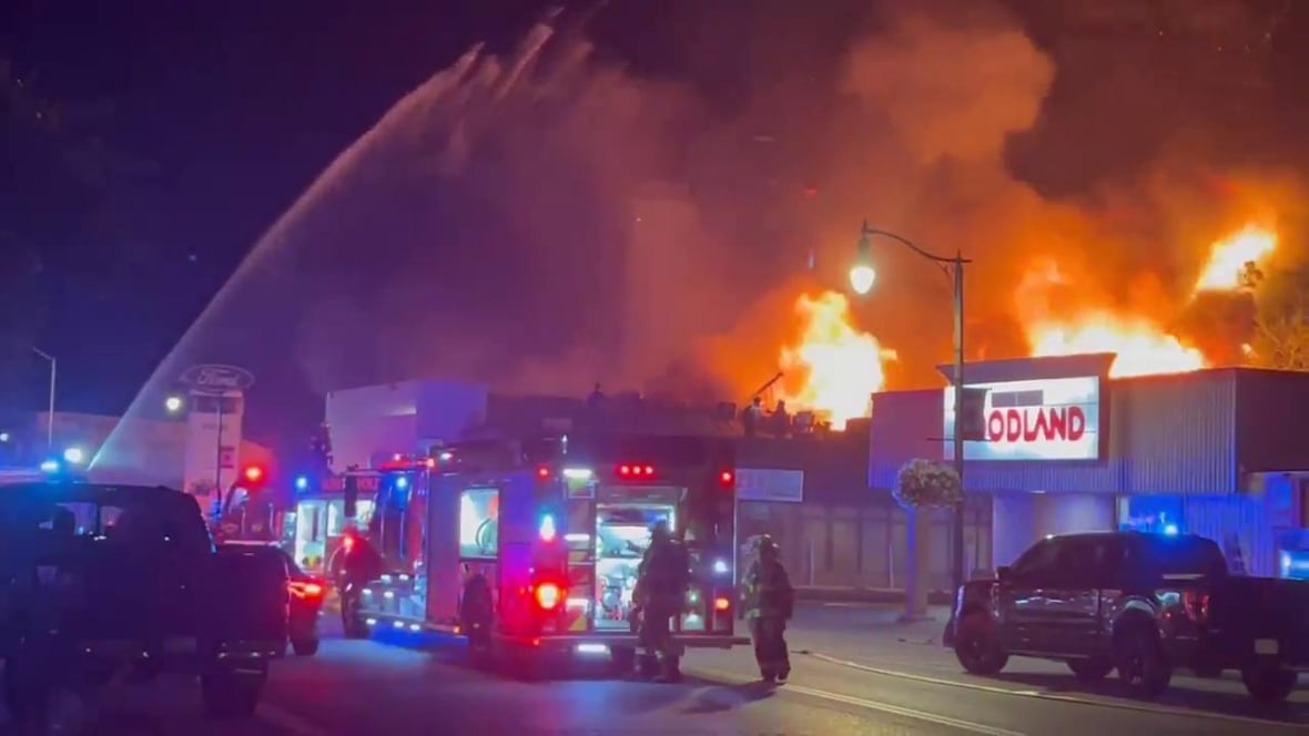 Fire crews conduct a defensive attack on a major blaze at Cotrac Ford Lincoln in Dutton on Wednesday, July 30, 2025. More than 50 firefighters from four different departments managed to keep flames from spreading to nearby businesses, including a neighbouring Foodland.
