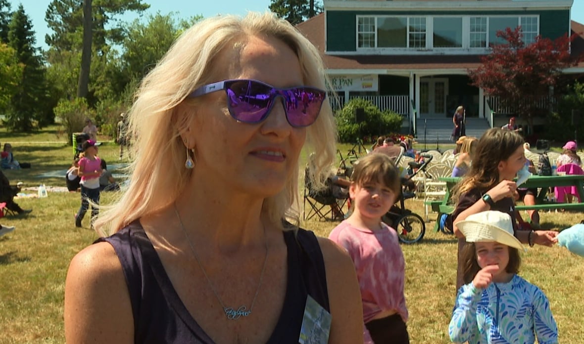Woman with blonde hair and sun glasses in park with lots of children