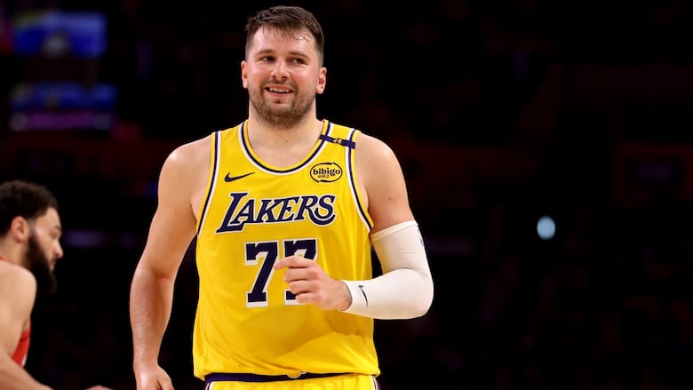 A male basketball player wearing number 77 for the Los Angeles Lakers smiles during a game.